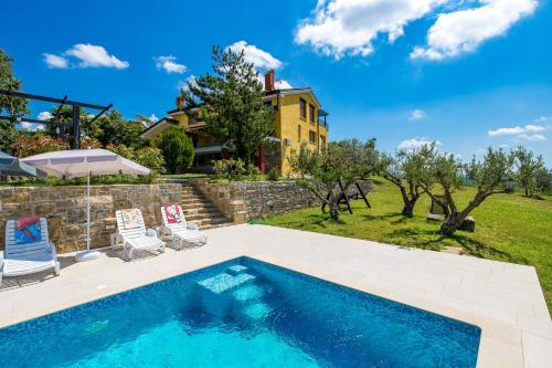 a swimming pool with two chairs and a house at Rona Apartment & Rooms Mea Vista in Buzet