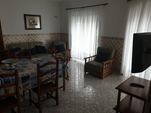 a living room with a bed and chairs and a tv at HOMELIDAYS CLARA NAZARE in Nazaré