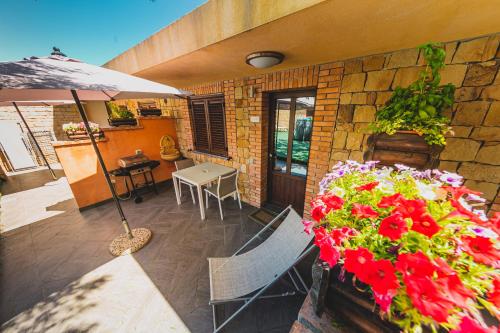 a patio with a table and flowers and an umbrella at Residence Cala Grande in Cefalù