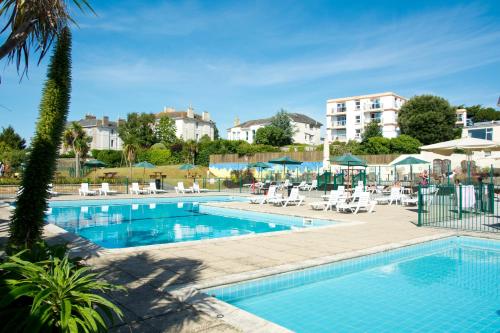 ein Pool mit Stühlen und ein Hotel in der Unterkunft TLH Derwent Hotel - TLH Leisure, Entertainment and Spa Resort in Torquay