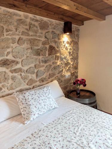 a bed in a room with a stone wall at Casa Rural La Bodega in Aldeadávila de la Ribera
