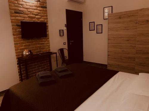 sypialnia z łóżkiem, telewizorem i ceglaną ścianą w obiekcie LoFT w mieście Bosa