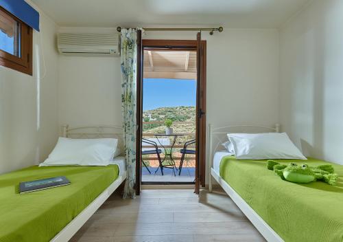 two beds in a room with a view of a balcony at Keramos Villa & Apartments in Agia Pelagia
