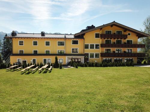 a large yellow building with lawn chairs in front of it at Mountain Hotel & Hostel in Ramsau am Dachstein