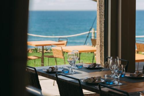 a table with wine glasses and a view of the ocean at Santa Barbara Eco-Beach Resort in Ribeira Grande