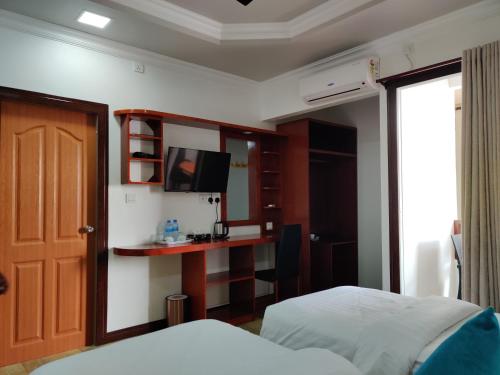 a bedroom with a bed and a tv on a wall at Athens View Hotel in Guraidhoo
