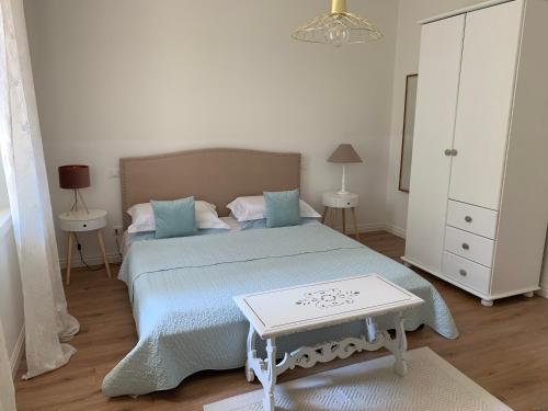 ein Schlafzimmer mit einem Bett mit einer blauen Decke und einem Tisch in der Unterkunft Al viale - a Negrar nel cuore della Valpolicella in Negrar