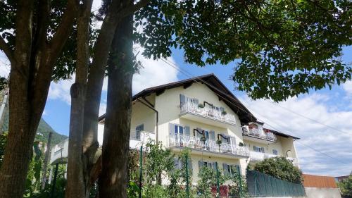 a large white building with balconies and trees at Strengen Guesthouse in Caldaro