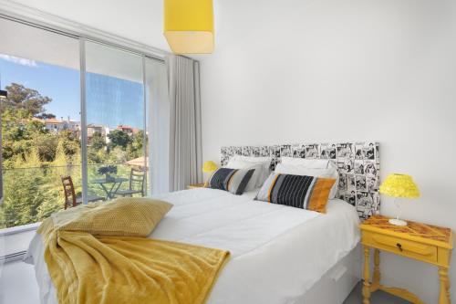 1 dormitorio con cama blanca y ventana grande en Miguel Bombarda - Porto Houses & Suites, en Oporto