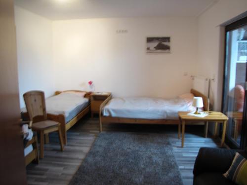 a room with two beds and a chair and a table at Fewo Ruhrblick com in Wickede (Ruhr)