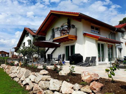 a house with chairs and an umbrella in front of it at Oberland-Ferienwohnung inkl Königscard bis zu 150 Attraktionen inkl in Unterammergau