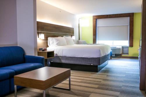 une chambre d'hôtel avec un lit et un canapé bleu dans l'établissement Holiday Inn Express Hotel & Suites Memphis/Germantown, an IHG Hotel, à Memphis
