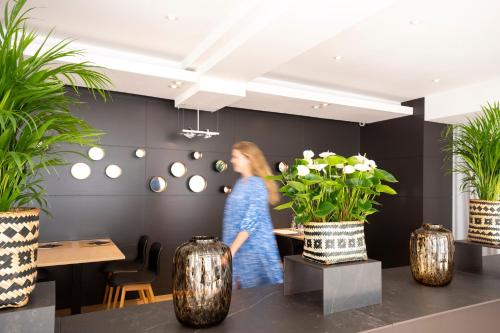 a woman walking in a room with plants at Hotel Nelson in Knokke-Heist