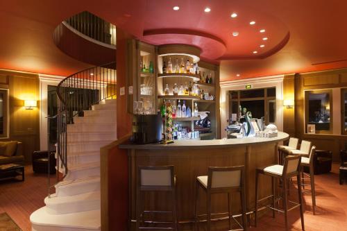 a bar in a restaurant with a staircase at Le Gingko - Hotel du Golf Parc Robert Hersant in La Chaussée-dʼIvry