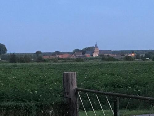 a fence in a field with a castle in the distance at familieverblijf De groene Specht in Sluis