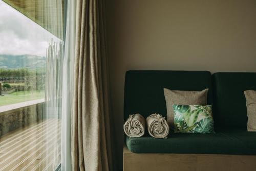 a green couch with two pillows on it next to a window at Santa Barbara Eco-Beach Resort in Ribeira Grande