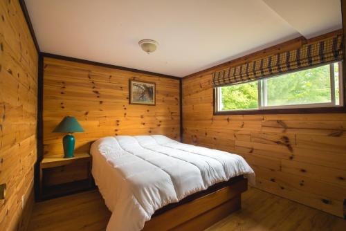 a bedroom with wooden walls and a bed in a room at Beautiful 3 Bdrm + Bunkie Waterfront Cottage Near Gull Lake in Minden