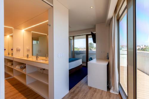 a bathroom with a sink and a bed and a mirror at Sea Porto Hotel in Matosinhos