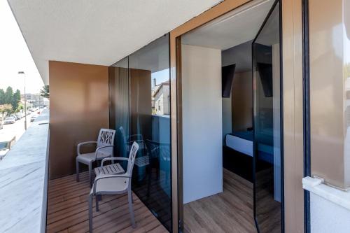 a room with glass walls and a balcony with chairs at Sea Porto Hotel in Matosinhos