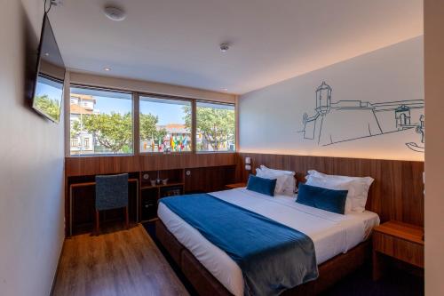 a bedroom with a large bed with a blue blanket at Sea Porto Hotel in Matosinhos
