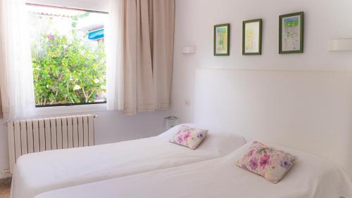 two beds in a room with a window at Es Norai 18 in Cala Ratjada