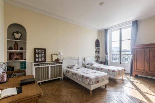 a bedroom with two beds and a desk and a window at Paris-sur-seine-chez-caroline in Paris