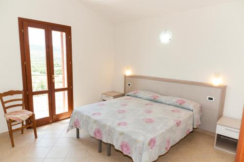 ブドーニにあるCorte di Galluraのベッドルーム1室(ベッド1台、椅子、窓付)