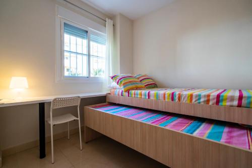 una camera da letto con due letti, una scrivania e una finestra di Playa Torrecilla Piscina Centro 2 Habitaciones a Nerja