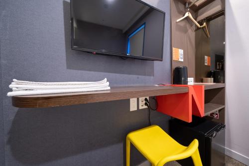 a desk with a yellow chair and a tv on a wall at Seoul N Guesthouse Dongdaemoon in Seoul
