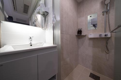 a white bathroom with a sink and a shower at Seoul N Guesthouse Dongdaemoon in Seoul