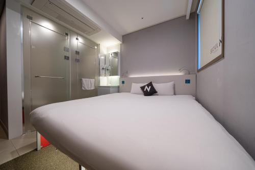 a large white bed in a small room with a shower at Seoul N Hotel Dongdaemun in Seoul