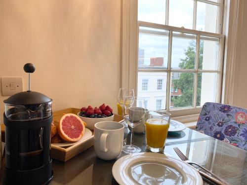 a table with a plate of fruit and glasses of orange juice at Stylish Apartments in Pimlico & Westminster in London