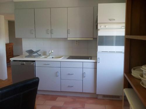Una cocina con gabinetes blancos y un fregadero. en L étoile, en Roussillon