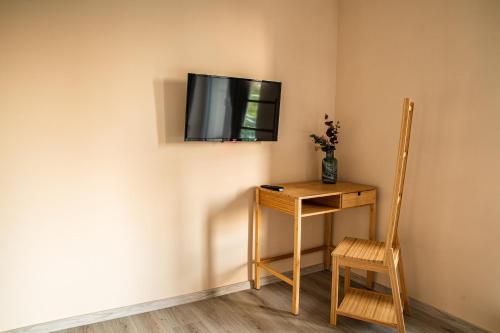 a television on a wall with a table and a chair at K-house in Liptovský Mikuláš