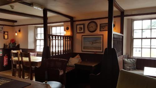 a restaurant with a table and chairs and a clock on the wall at The Antelope at Upavon in Upavon