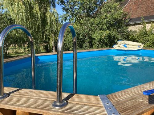 a pool with metal rails next to a wooden deck at Chambres d'hôtes La Ferme du Grand Launay in Semblançay