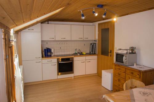 Il comprend une cuisine avec des placards blancs et un plafond en bois. dans l'établissement Kehrerhof, à Ellbögen