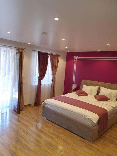 a bedroom with a large bed with a purple wall at Casa Stefandra in Breaza