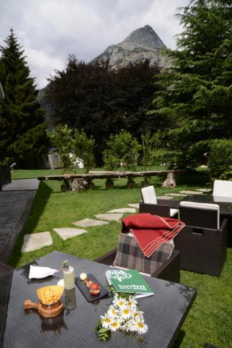 a table and chairs in a garden with a mountain in the background at Grand Hotel Royal E Golf in Courmayeur
