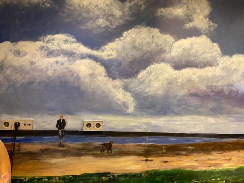 a painting of a man and a dog on the beach at Het Huis van de Wadden in Den Oever
