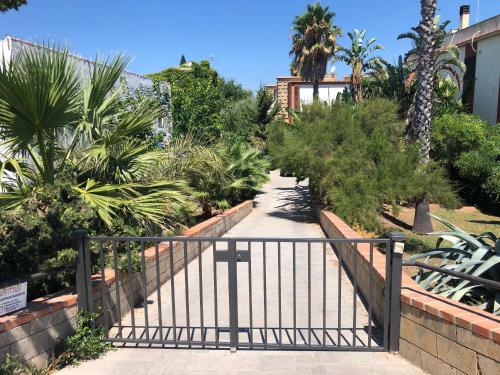 a gate leading to a walkway with palm trees at Appartamentino in villa sul mare in Noto Marina