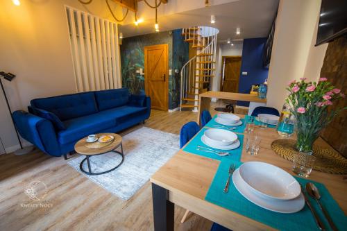 Apartamenty "Kwiaty Nocy" i "W Krainie Mchu" - Wisła في فيسلا: غرفة معيشة مع أريكة زرقاء وطاولة