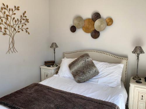 a bedroom with a bed with white sheets and two night stands at Lalapanzi in Fish hoek