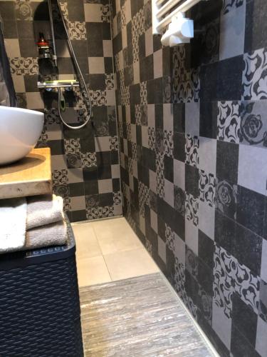 a bathroom with a black and white tiled wall at Het Huis van de Wadden in Den Oever
