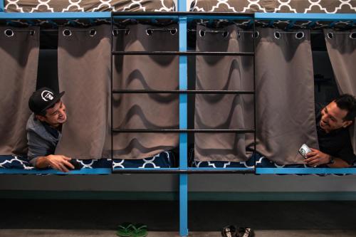 two men sitting on a shelf with curtains at California Dreams Hostel - Pacific Beach in San Diego