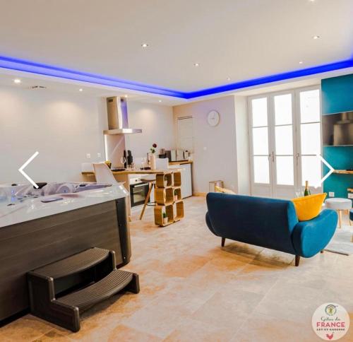 a living room with a blue couch and a kitchen at Le loft en bulles in Saint-Maurin