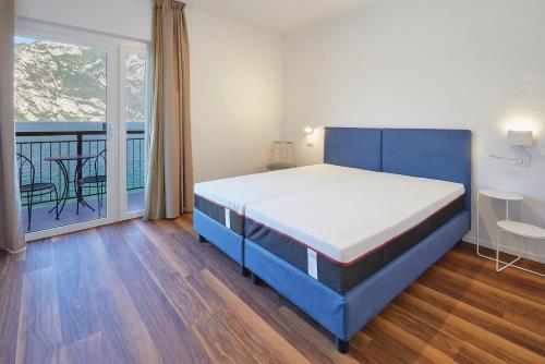 a bedroom with a blue bed and a balcony at Hotel Paradiso Conca d'Oro in Nago-Torbole