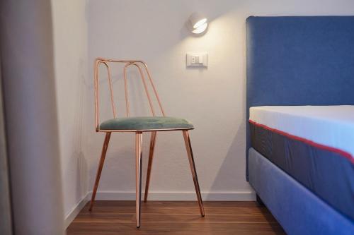 a chair sitting in a room next to a bed at Hotel Paradiso Conca d'Oro in Nago-Torbole