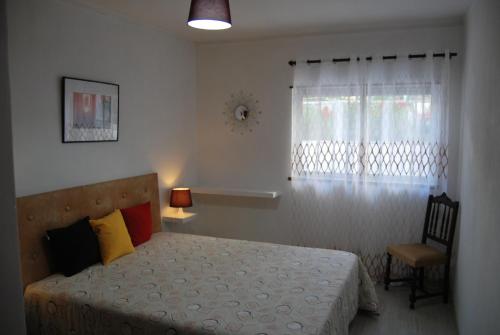 una camera con letto, finestra e sedia di Apartamentos Mota a Nazaré