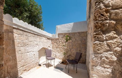 two chairs sitting on a patio next to a stone wall at La Regina Veneziana in Mağusa